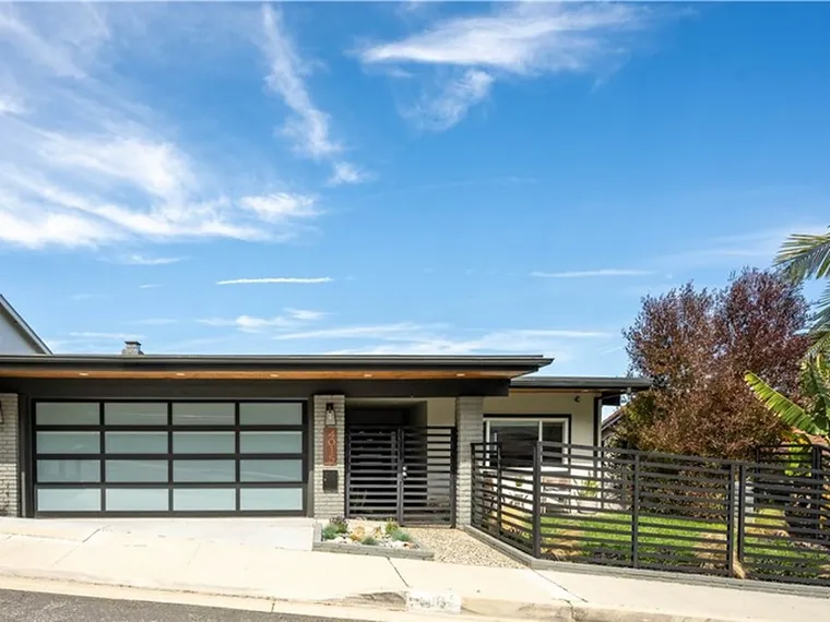 Single-level modern home with a glass-panel garage door and a dark horizontal slat fence at 4015 Paseo De Las Tortugas, Torrance, California