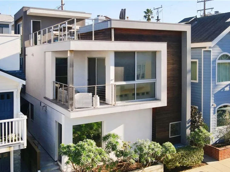 Modern white stucco and dark wood three-level home with a cable-rail balcony and rooftop deck at 44 61st Place, Long Beach, California